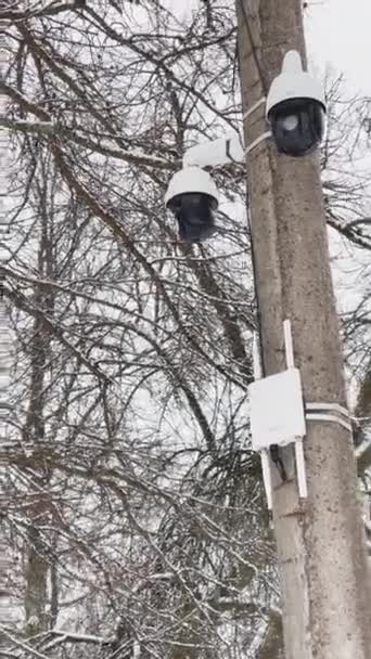 Rusia, San Petersburgo, 22 de marzo de 2021: El metraje vertical de la cámara de vigilancia cuelga de una columna de hormigón, un enrutador de una comunicación inalámbrica con antenas, los árboles sin hojas sobre un fondo — Vídeos de Stock