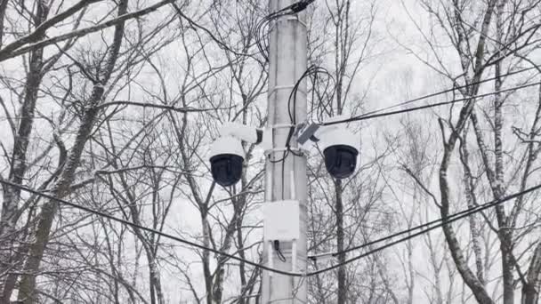 Russie, Saint-Pétersbourg, 22 mars 2021 : La caméra de surveillance est suspendue sur une colonne de béton, un routeur d'une communication sans fil avec des antennes, les arbres sans feuilles sur un fond — Video