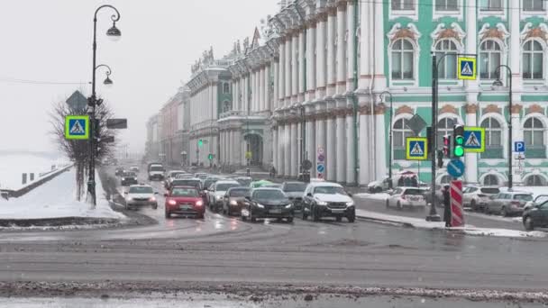 Rusia, San Petersburgo, 03 de febrero de 2021: El tráfico de automóviles en el terraplén del palacio en el museo de la Ermita o el Palacio de Invierno en el día nublado de invierno, la suciedad en las carreteras, está nevando — Vídeo de stock