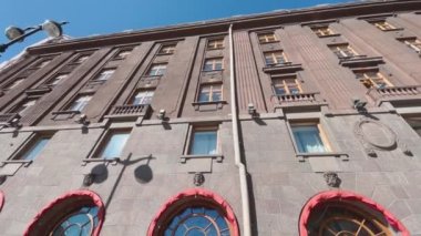 Güneşli bir havada, güzel antik binanın ön yüzü, alttaki manzara, kırmızı renkli güneş koruma zirveleri, büyük pencereler, mavi gökyüzü, geniş bir merceğin etkisi, Rusya, St. Petersburg