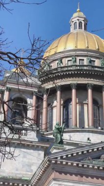 St. Isaacs Katedrali 'ndeki Colonnade' in dikey görüntüleri ağaçların dalları arasında güneşli bir havada, ilk güneşli günlerde, yavaş çekimde.