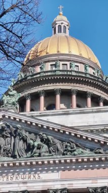 St. Isaacs Katedrali 'ndeki Colonnade' in dikey görüntüleri ağaçların dalları arasında güneşli bir havada, ilk güneşli günlerde, yavaş çekimde.