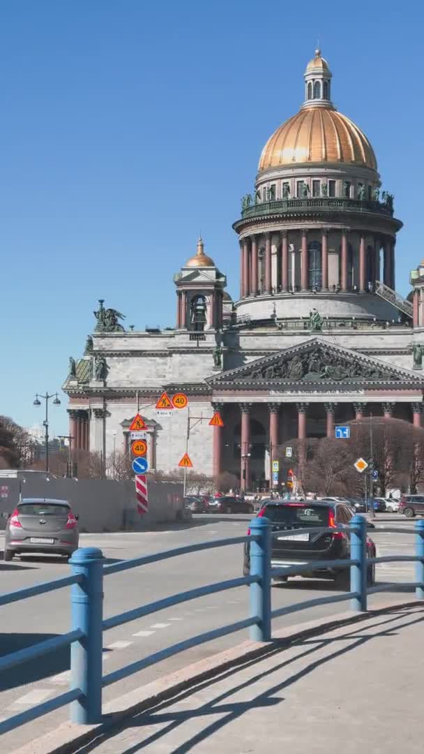 ロシア, St.Petersburg, 01 April 2021:晴れた日の聖イサク大聖堂の垂直映像,春の最初の晴れた日,歩行者,車の交通 — ストック動画