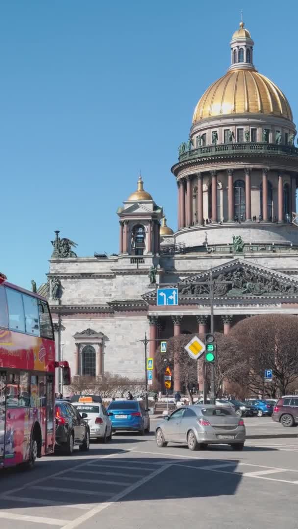 Russia, St.Petersburg, 01 April 2021: Vertical footage of St. Isaacs Cathedral at the sunny weather, the first sunny days of the spring, walking people, car traffic, Excursion Red Bus — Stock video