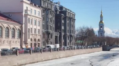 Rusya, St. Petersburg, 01 Nisan 2021: Açık güneşli bir bahar gününde Aziz Nicholas Donanma Katedrali çan kulesi, Kryukov ve Griboyedov Kanalı 'nda bir buz akıntısı, toprak setten yedi köprü manzarası