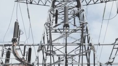 Elektrik kablolarıyla yüksek gerilimli dev metal kule, alt görüş yukarı, video kameranın yavaş hareketi, bulutlu hava