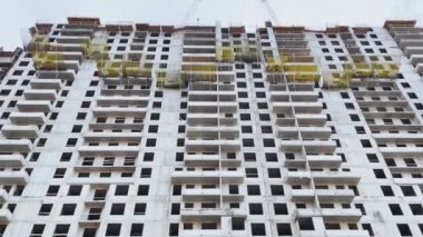 Rusya, St.Petersburg, 03 Nisan 2021: Yüksek katlı evin inşaatı, inşaat vinçleri, alttaki görüntü, video kameranın yavaş hareketi, penceresiz beton bloklar, büyük gayrimenkul