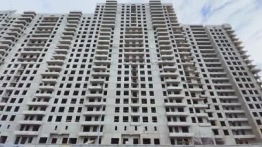 Üst kattaki evin inşaatı, inşaat vinçleri, alttaki görüntü, video kameranın yavaş hareketi, penceresiz beton bloklar ve cephe sonu, bulutlu hava, büyük bir emlak.