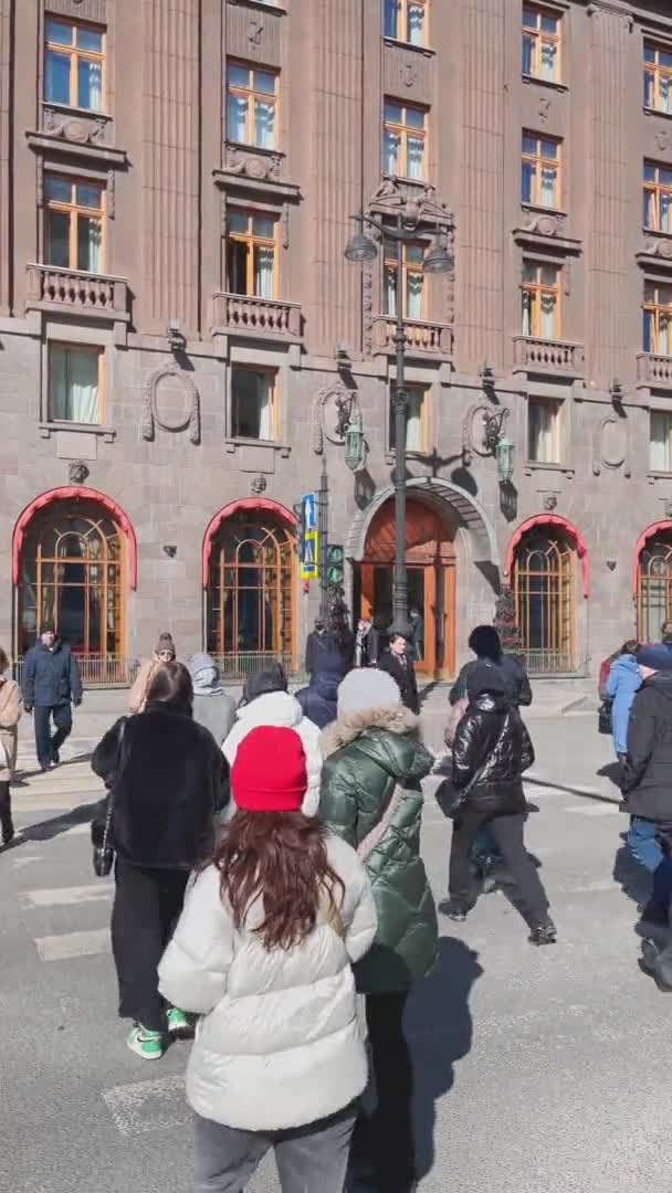 Rusya, St.Petersburg, 01 Nisan 2021: Yaya geçidinden yaya geçitleri, şık gençler ve yaşlılar, arka planda açık güneşli bir havada antik güzel binanın ön cephesi — Stok video