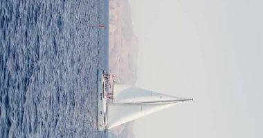 Türkiye, 05 Ekim 2020: Adam tekneye bağlı şişirilebilir bir tahtanın üzerinde, kauçuk teknede eğleniyor açık güneşli bir günde, tekne yelkenliye bağlı, parlak duygular içinde