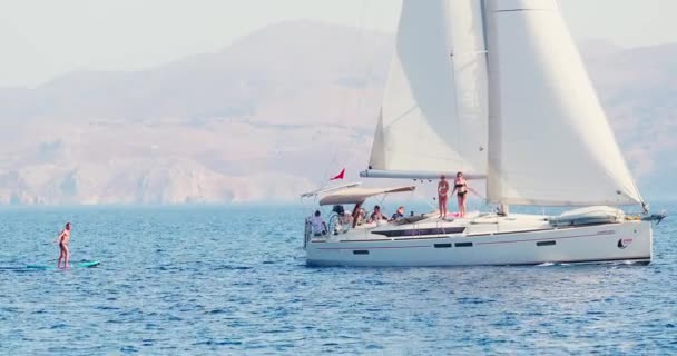 Turquie, 05 octobre 2020 : L'homme est sur une planche gonflable attachée au bateau avant, il s'amuse par le bateau en caoutchouc une journée ensoleillée claire, le bateau est attaché au voilier, émotions vives — Video