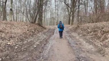 Ayakları sopalı gezginin dikiz aynası, ormandaki bir tepede yükselir, sırtında sırt çantası asılır, mavi renkli ceket.