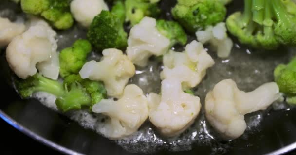 Le verdure tagliate fresche sono fritte su una padella per friggere, un cavolfiore, broccoli, fagiolo bianco, un piatto lucente e dietetico, tutto questo è fritto su oli cremosi, olio lentamente bolle, uno stile di vita sano — Video Stock