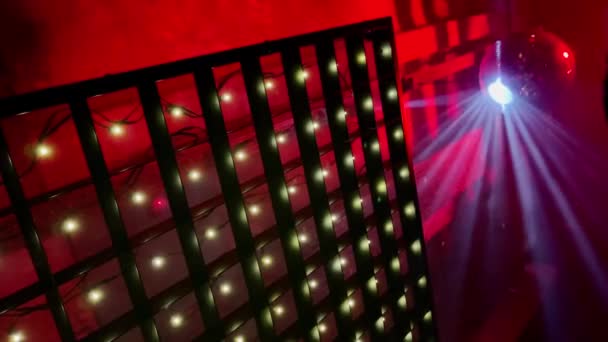 Die große Discokugel rotiert mit vielen Lichtstrahlen weißer Farbe in einem Rauch drinnen, Innenräume roter Farbe auf Hintergrund, Clubatmosphäre, Stoffstil, Strahlen leuchten in einer Linse, Partyzeit, Spaß — Stockvideo