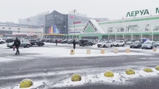 Rusko, Petrohrad, 18. března 2021: Silný sníh v městském ruchu, parkoviště u obrovského nákupního centra, sněhová bouřka, sněhová bouřka, na budově pestrobarevné cedule — Stock video