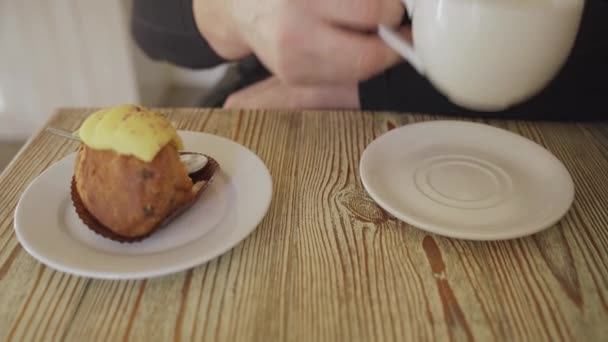 De persoon drinkt zwarte koffie en zet een kopje koffie op een tafel, op een tafel is er een bord met gele room taart, de tafel is gemaakt van een natuurlijke boom, ware van witte kleur — Stockvideo