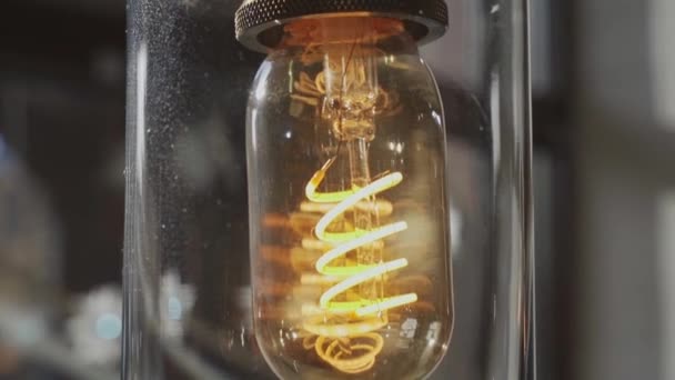 The decorative lamp with an incandescence thread in an interior, a lamp is in a glass flask, Edisons lamp, a close up — Stock Video