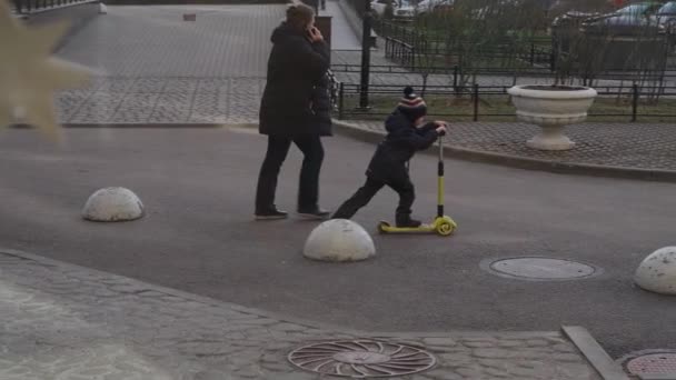 Rússia, São Petersburgo, 11 de abril de 2021: A criança monta um skate sob a supervisão dos pais no quintal da casa, vídeo lento — Vídeo de Stock