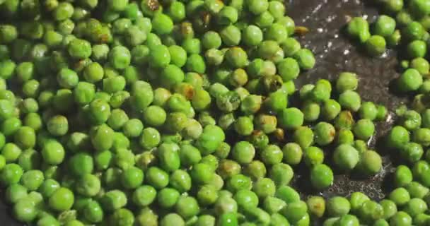 Nahaufnahme der Küchenschaufel mit roter Farbe mischt grüne Erbsen, die auf einer Pfanne zubereitet werden, ein helles und diätetisches Gericht, ein gesunder Lebensstil — Stockvideo