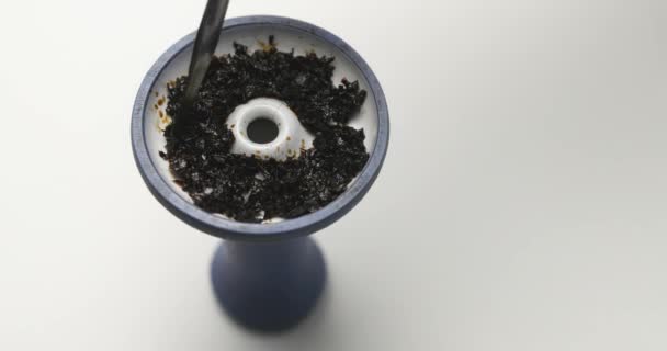 Smoking Tobacco for a hookah put with nippers in a special bowl and display around, the bowl of blue and white color, a bowl is on a white table — Stock Video