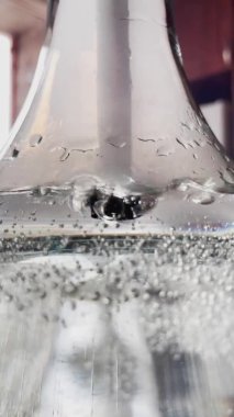 Su, nargile şişesi, matara duvarlarında hava şişeleri olan cam bir kaptaki tüpten çıkan baloncukların soyut bir videosu.