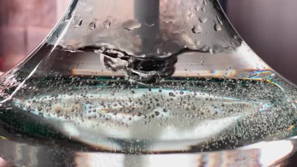 Primer plano video abstracto en cámara lenta de burbujas de un tubo en un recipiente de vidrio con agua, un frasco de narguile, frascos de aire en las paredes del frasco, 24 fps — Vídeos de Stock