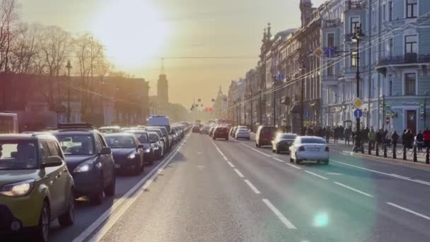Rusland, Sint-Petersburg, 14 april 2021: De architectuur van Nevsky Prospect bij zonsondergang tijdens autoverkeer, het poppentheater, veel transportvoertuigen, lange schaduwen van mensen en auto 's — Stockvideo