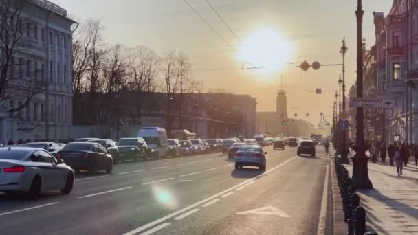 Rusland, Sint-Petersburg, 14 april 2021: De architectuur van Nevsky Prospect bij zonsondergang tijdens autoverkeer, het poppentheater, veel transportvoertuigen, lange schaduwen van mensen en auto 's — Stockvideo