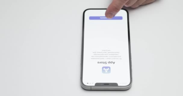 Rusya, St.Petersburg, 09 Nisan 2021: Beyaz masa arkaplanındaki iPhone 12 Pro Max 'in karşılama ekranı, uygulama mağazasındaki Rus uygulamalarının kurulum teklifi, eller ekrana dokunuyor — Stok video