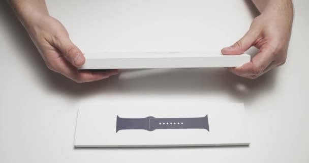Rusya, St.Petersburg, 16 Nisan 2021: Beyaz renkli bir masada Apple Watch serisinin 644 metrelik yeni bir saatinin paketini açan kişi, içinde yeni bir cihaz bulunan bir kutuyu açıyor ve eksiksiz bir set izliyor — Stok video