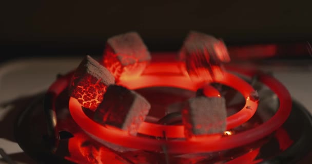Carboni ardenti rossi per narghilè riscaldati su stufa elettrica, preparare shisha a casa, ceneri, pinze speciali prendono carbone da un elemento di incandescenza, scintille volano — Video Stock