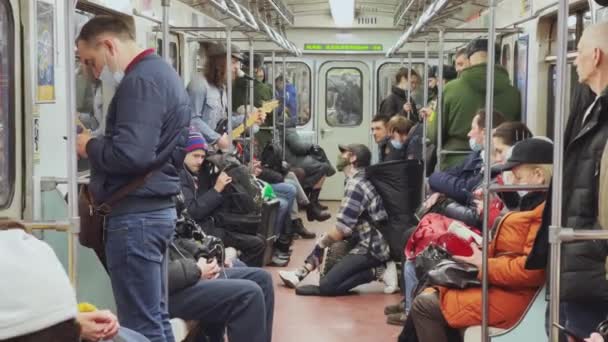 Rússia, São Petersburgo, 11 de abril de 2021: Músicos tocam no carro do metrô, pessoas com máscaras higiênicas, pessoas cansadas vão atrás do trabalho, alguém usa o smartphone — Vídeo de Stock