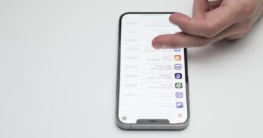 Rusya, St.Petersburg, 09 Nisan 2021: Beyaz masa arkaplanındaki iPhone 12 Pro Max 'in karşılama ekranı, uygulama mağazasındaki Rus uygulamalarının kurulum teklifi, eller ekrana dokunuyor