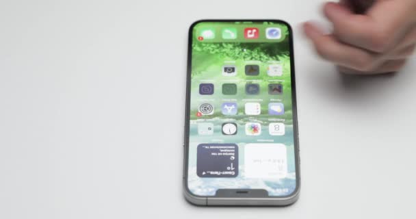 Russia, San Pietroburgo, 09 Aprile 2021: A Lo schermo di saluto di iPhone 12 Pro Max su sfondo bianco tavolo, l'installazione di applicazioni, mani toccare lo schermo — Video Stock