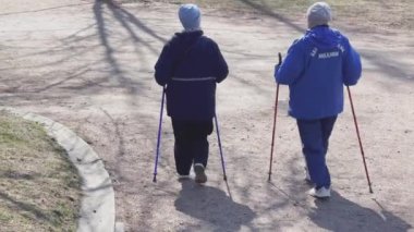 Rusya, S.Petersburg, 22 Nisan 2021: Yaşlılar grubu güneşli bahar havasında parkta çubuklarla spor yapma konusunda fiziksel egzersiz yapıyor