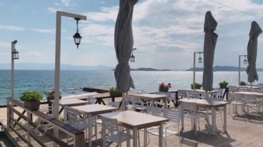 Yunanistan 'ın İyon Denizi kıyısındaki açık bir terasta ziyaretçisi olmayan boş bir kafe. Salgın Covid-19 sırasında güneşli bir hava var.