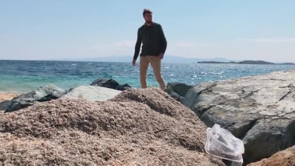 Mladý muž dobrovolník vyčistí jemnou plastovou pláž, obává se, že planeta je zaneřáděná, Použitá plastová krabice v popředí — Stock video