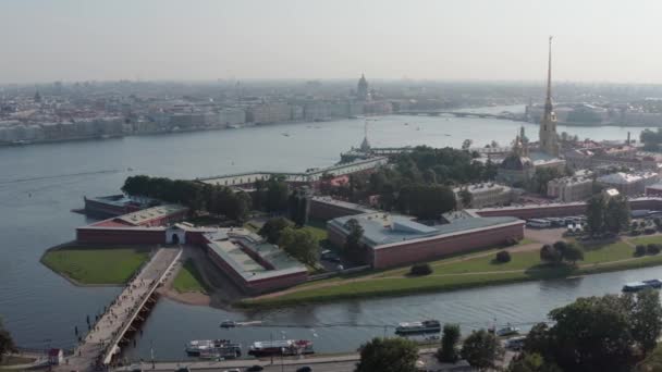 Luftaufnahmen der Peter-und-Paul-Festung in St. Petersburg Russland bei sonnigem Wetter, im Hintergrund das Zentrum der Stadt, der Fluss Newa, der Autoverkehr auf der Straße, Drohnen fliegen von links nach rechts — Stockvideo