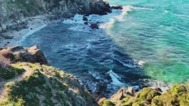 Gün doğumunda boş bir halk plajı olan mavi bir göl manzarasının yavaş çekim görüntüleri, Rocky sahili, arka planda turistler olmadan dağlar, masmavi su.