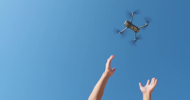 Lényegében egy repülő drón mozdulatlan ellen a kék ég napsütéses időben, Kezek nyúlnak egy drón, érzékelők és egy kamera, pengék mozgásban, közelkép — Stock videók