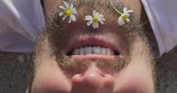 Białe kwiatki w brodzie uśmiechniętego mężczyzny, wakacje na plaży, zadowolona twarz mężczyzny, jest ubrany w białą koszulkę, relacje między mężczyzną a kobietą, miesiąc miodowy — Wideo stockowe