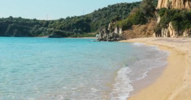 Güneşin doğuşunda boş bir halk plajı olan mavi bir göl manzarası, Rocky sahili, arka planda turistsiz dağlar, masmavi su.