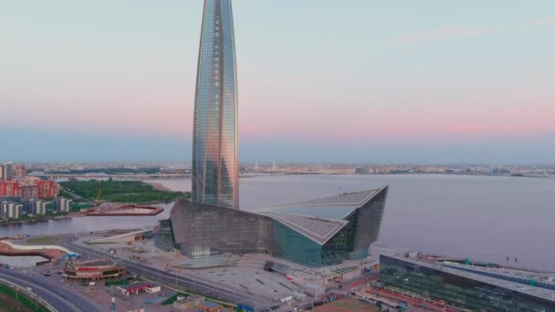 Oroszország, Szentpétervár, 2021. május 16.: Drone point of highest skyscraper in Europe Lakhta Center at pink sunset, Headquarters of the oil company Gazprom, stadium Gazprom Arena on background — Stock videók