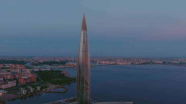 Russland, St.Petersburg, 16. Mai 2021: Fluchtdrohne vom höchsten Wolkenkratzer Europas Lakhta Center bei rosa Sonnenuntergang, Hauptquartier des Ölkonzerns Gazprom, Stadion Gazprom Arena im Hintergrund — Stockvideo