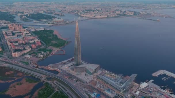 Rusko, Petrohrad, 16. května 2021: Dron odletu z nejvyššího mrakodrapu v Evropě Lakhta Center při růžovém západu slunce, ústředí ropné společnosti Gazprom, stadion Gazprom Arena na pozadí — Stock video