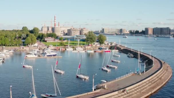 Russland, St. Petersburg, 01. September 2020: Die Drohne fliegt bei sonnigem Wetter über den Yachtclub, Segelboote auf einem Parkplatz, ein halbrunder Steg, die flotte Böschung — Stockvideo