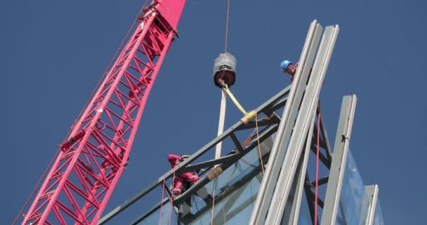Россия, Санкт-Петербург, 14 августа 2020 года: Строительство небоскреба "Лахта" для нефтяной компании "Газпром", фасадное остекление, строители поднимают большие бокалы на высоту с помощью высотного строительного крана — стоковое видео