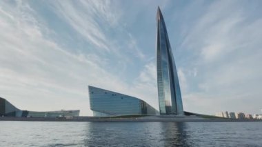 Rusya, St. Petersburg, 18 Haziran 2021: Petrol şirketi Gazprom için gökdelen inşaatı Lakhta, açık havada parlayan bir cephe, bina zirvesi, bir binanın yanındaki su