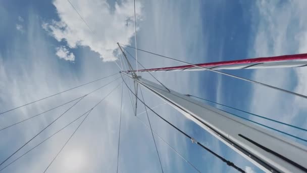 Het onderste uitzicht op een mast van de zeilboot, een zeil worden ingekort, een helder zonnig weer, de blauwe lucht met wolken, rond video — Stockvideo