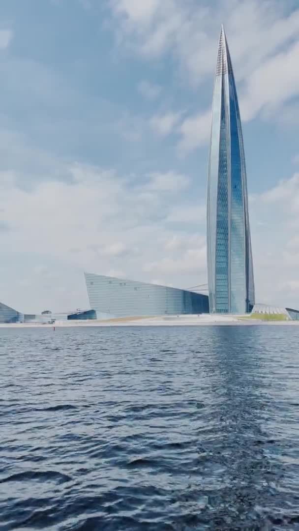 Russland, St. Petersburg, 18. Juni 2021: Blick vom Wasser auf den Wolkenkratzer Lakhta Center, Gebäude des Ölkonzerns Gazprom, Fassadenverglasung bei klarem Wetter, Gebäudespitze, Wasser in der Nähe eines Gebäudes — Stockvideo